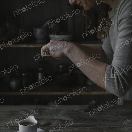 A woman taking a photograph from above of a cup and saucer on a kitchen table. A woman taking a photograph from above of a cup and saucer on a kitchen table.