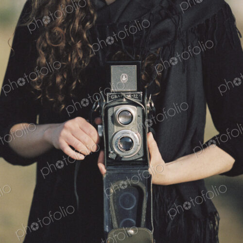 A woman taking a picture with an old fashioned medium format camera.