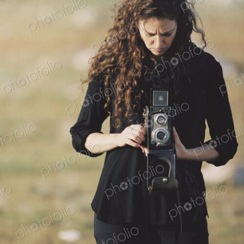 A woman taking a picture with an old fashioned medium format camera.