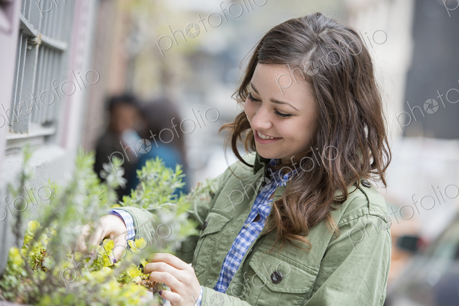 A woman tending a window box on a city street. Spring flowers.