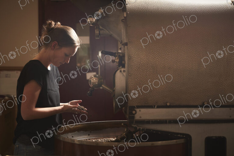 A woman testing a handful of roasted coffee beans.