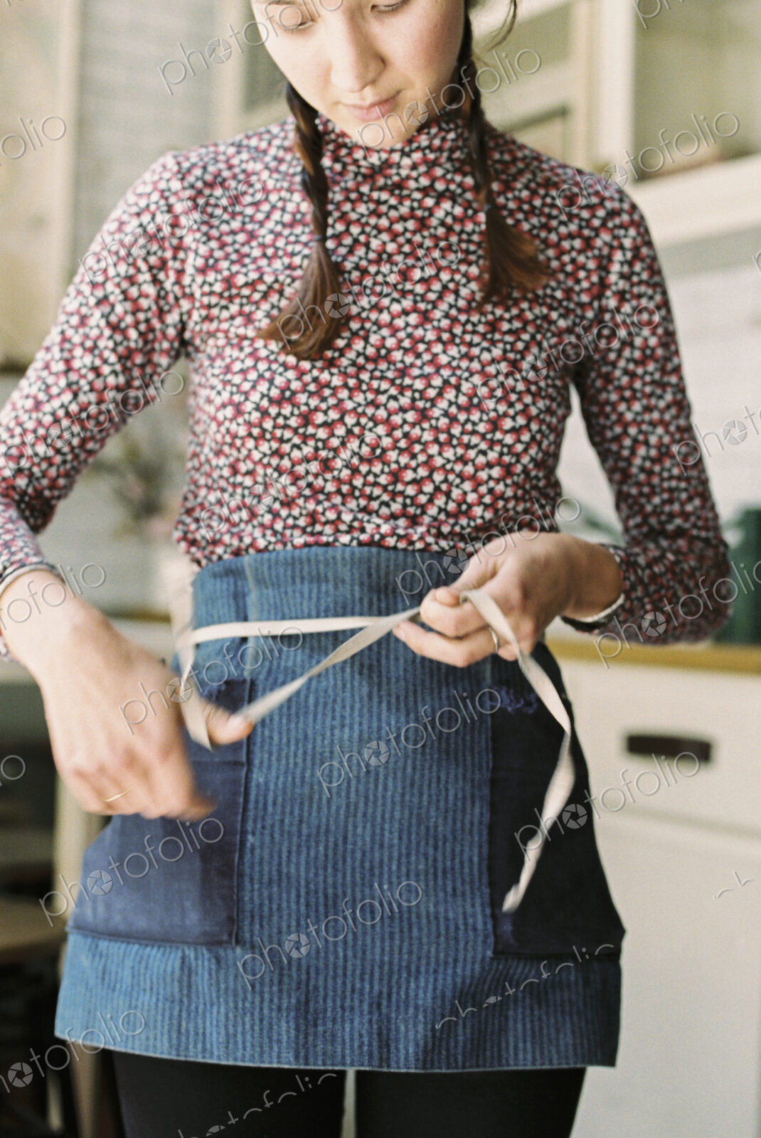A woman tying the tapes of an apron aroud her waist.