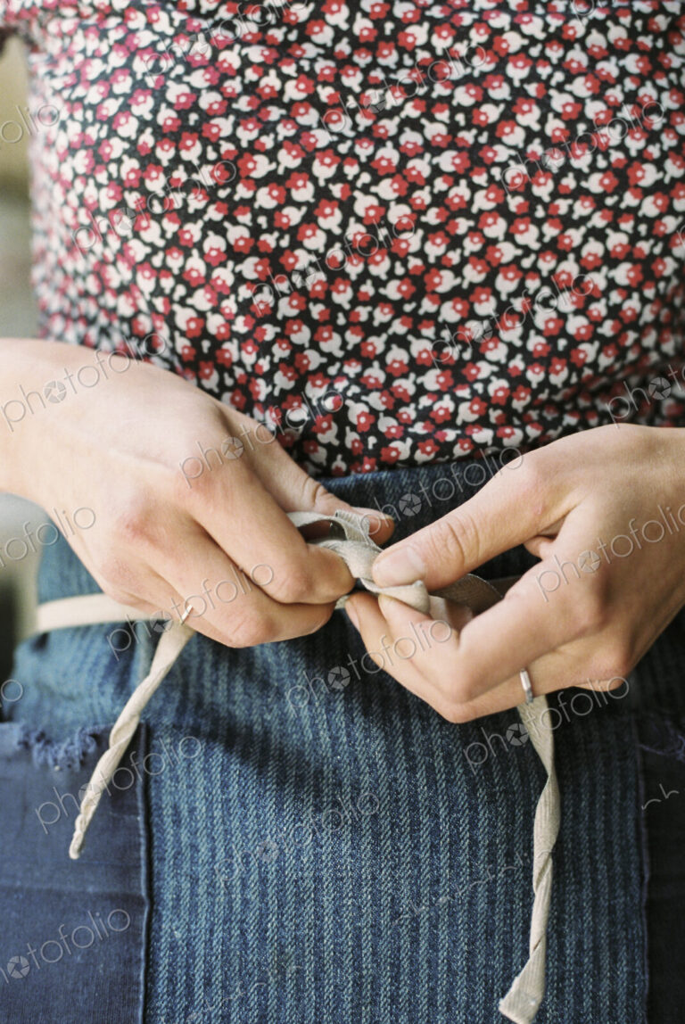 A woman tying the tapes of an apron aroud her waist.
