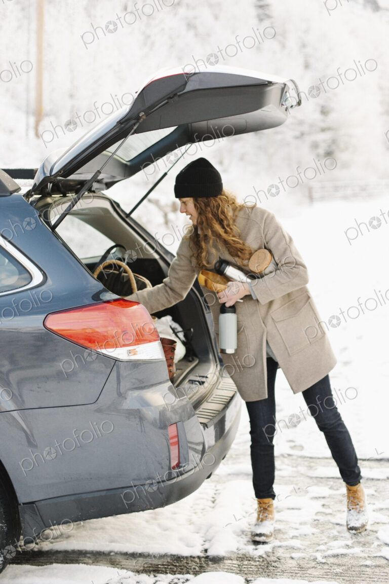 A woman unloading the shopping from the boot of a car.