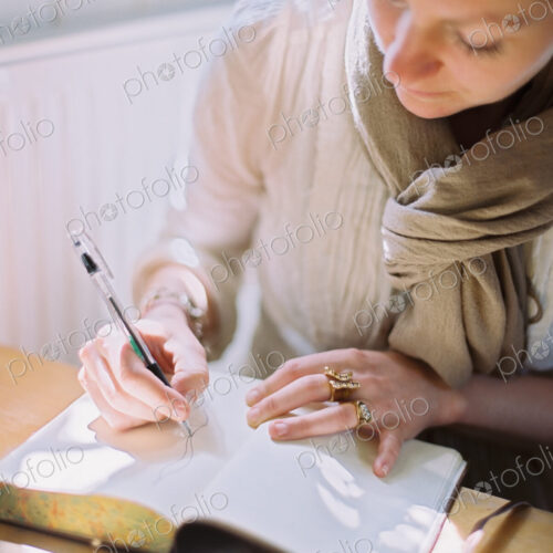 A woman using a coloured pen drawing on a blank page of a diary.