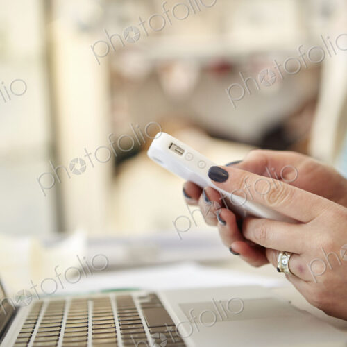 A woman using a laptop and a smart phone, making calls, running a business.