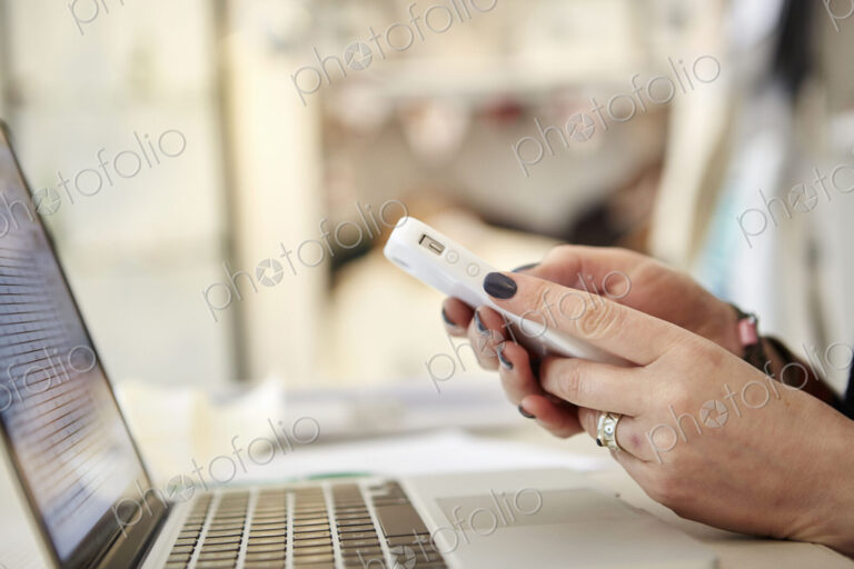 A woman using a laptop and a smart phone, making calls, running a business.