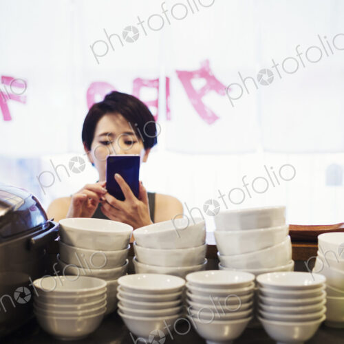 A woman using a smart phone at a noodle shop. A woman using a smart phone at a noodle shop.
