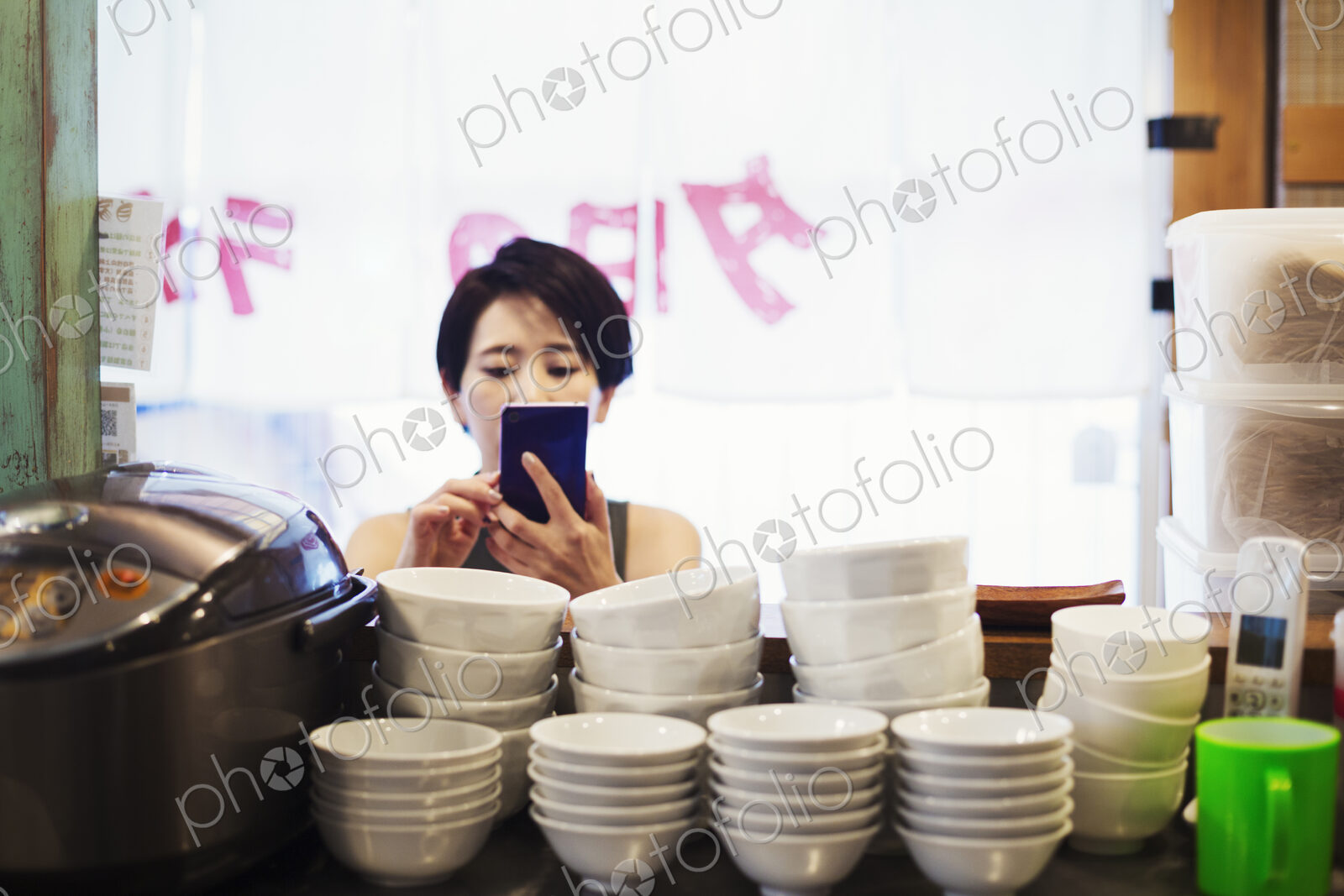 A woman using a smart phone at a noodle shop.