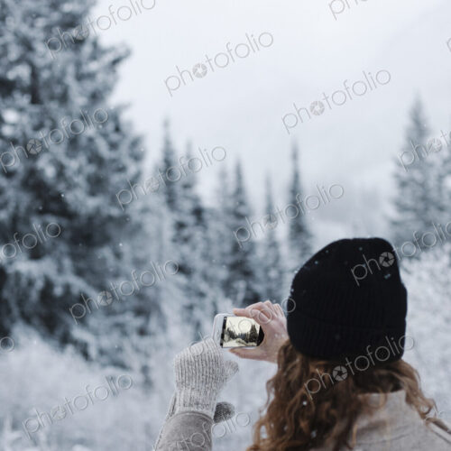 A woman using a smart phone, photographing pine forests in snow, A woman using a smart phone, photographing pine forests in snow,