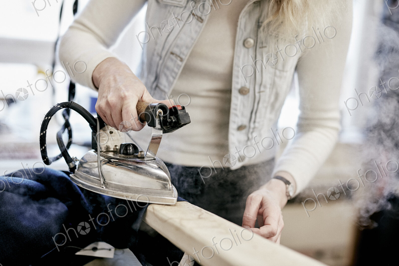 A woman using a steam iron on a new jacket, pressing the newly made garment.