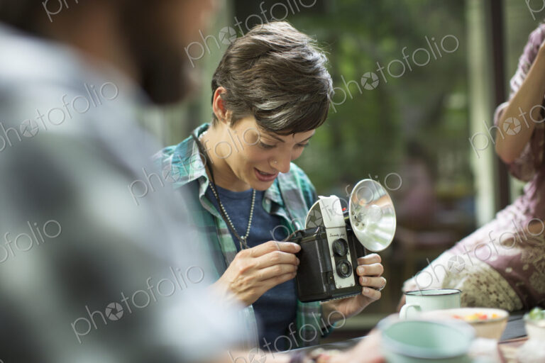 A woman using a vintage camera with separate metal flash unit.