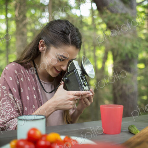 A woman using a vintage camera with separate metal flash unit. A woman using a vintage camera with separate metal flash unit.
