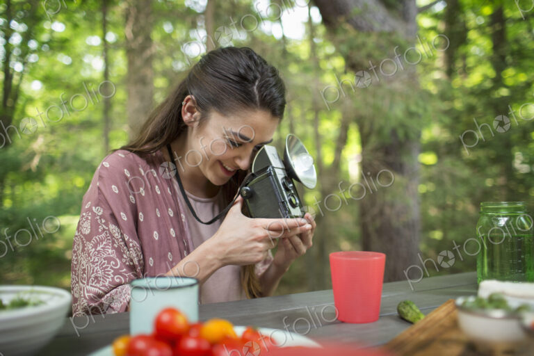 A woman using a vintage camera with separate metal flash unit.