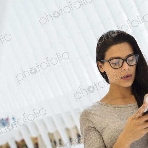 A woman using her smart phone, checking social media and messages, under the atrium… A woman using her smart phone, checking social media and messages, under the atrium…