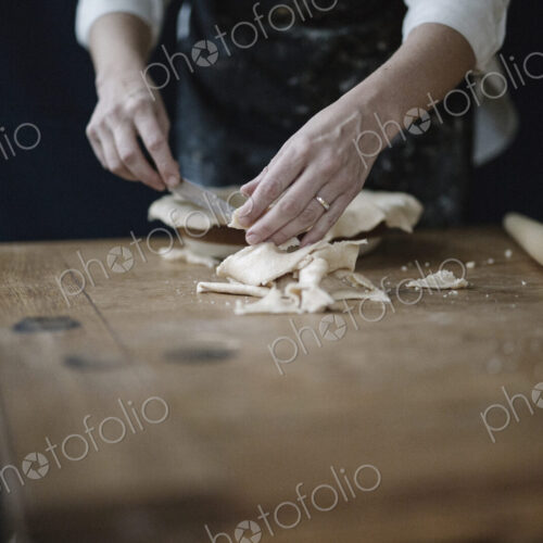 A woman using raw pastry dough to line a pie dish and finish the edge.