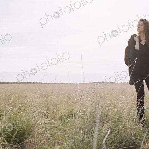 A woman walking across a grassy landscape with a bag over her shoulder. A woman walking across a grassy landscape with a bag over her shoulder.