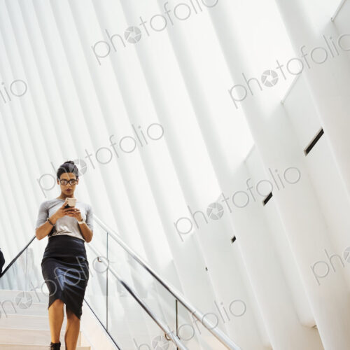 A woman walking down a staircase in a large open atrium space, a modern building. A woman walking down a staircase in a large open atrium space, a modern building.