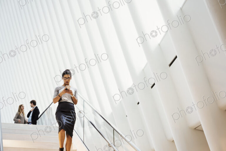 A woman walking down a staircase in a large open atrium space, a modern building.