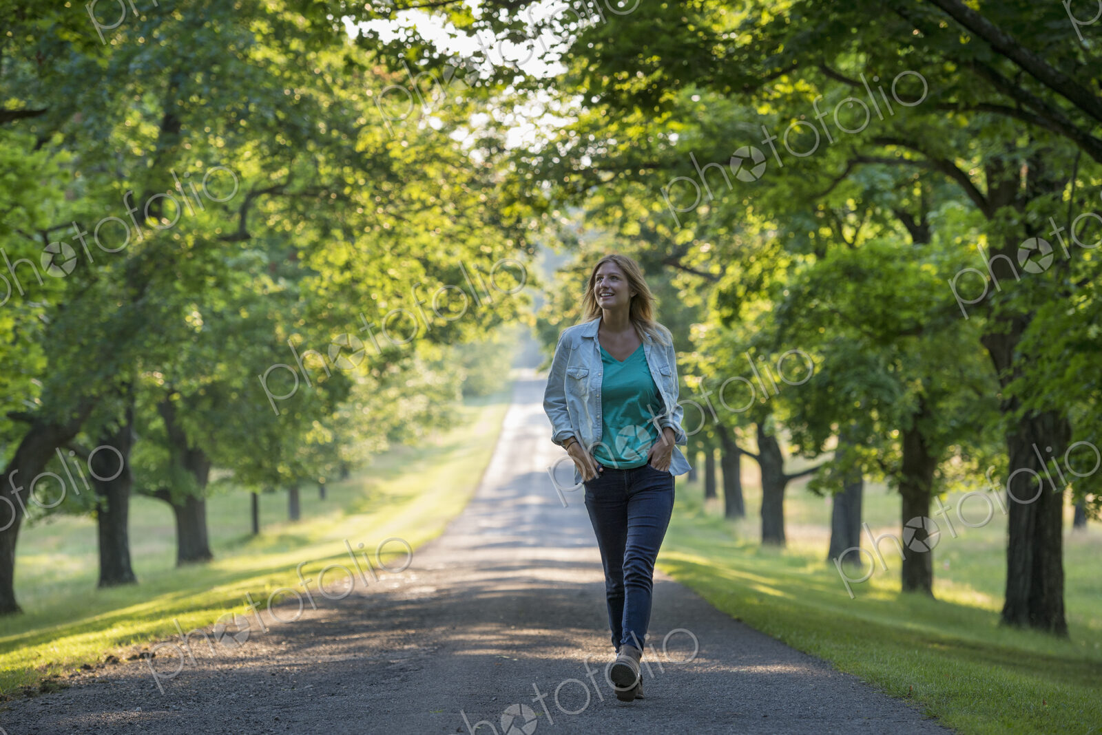A woman walking down a tree lined path.