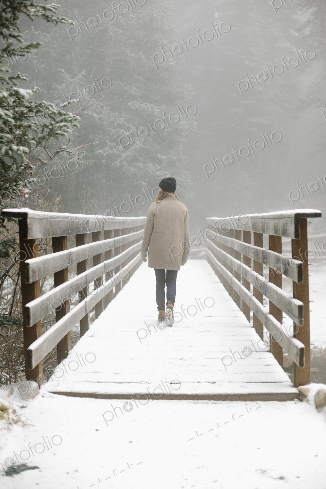 A woman walking on a footbridge in the mountains in snow.