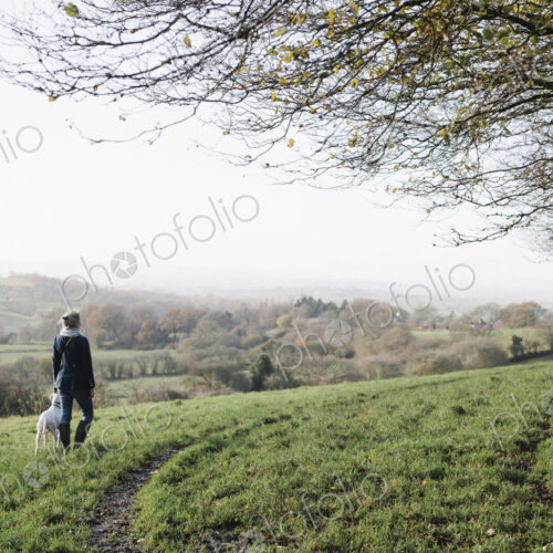A woman walking with a dog on high ground overlooking the countryside. A woman walking with a dog on high ground overlooking the countryside.