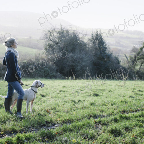 A woman walking with a dog on high ground overlooking the countryside. A woman walking with a dog on high ground overlooking the countryside.