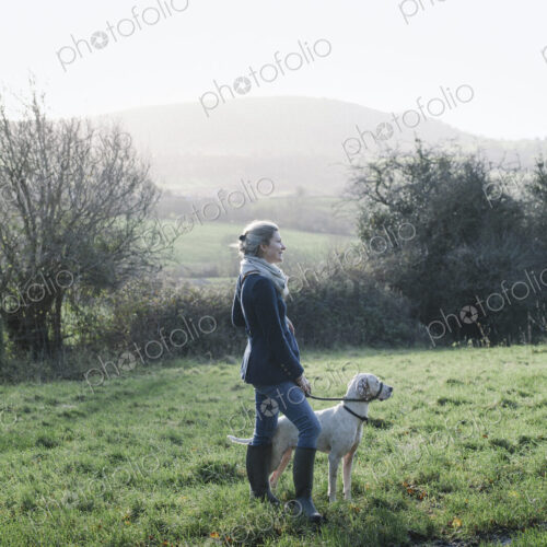 A woman walking with a dog on high ground overlooking the countryside. A woman walking with a dog on high ground overlooking the countryside.