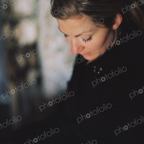 A woman wearing a black coat, looking down in a pensive mood. A woman wearing a black coat, looking down in a pensive mood.