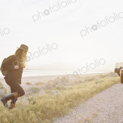 A woman wearing a hat and carrying a backpack near a 4x4 car, A woman wearing a hat and carrying a backpack near a 4x4 car,