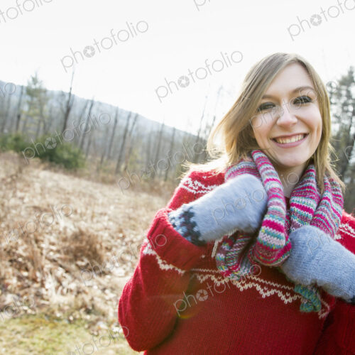 A woman wearing a knitted scarf and woolen mittens outdoors on a winter day. A woman wearing a knitted scarf and woolen mittens outdoors on a winter day.