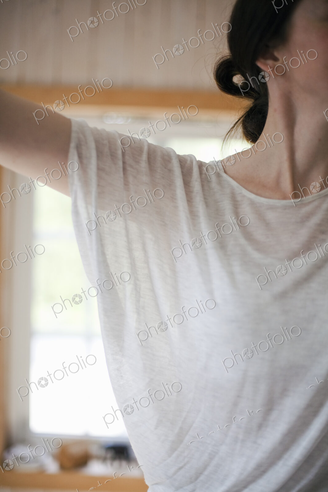 A woman wearing a light tee shirt, with her hair neatly tied back in a clip.…
