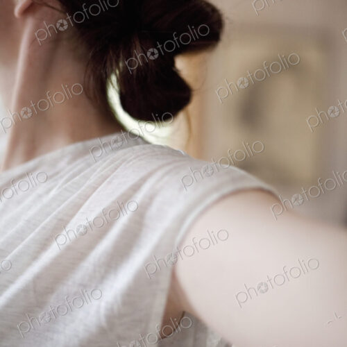 A woman wearing a light tee shirt, with her hair neatly tied back in a clip.…