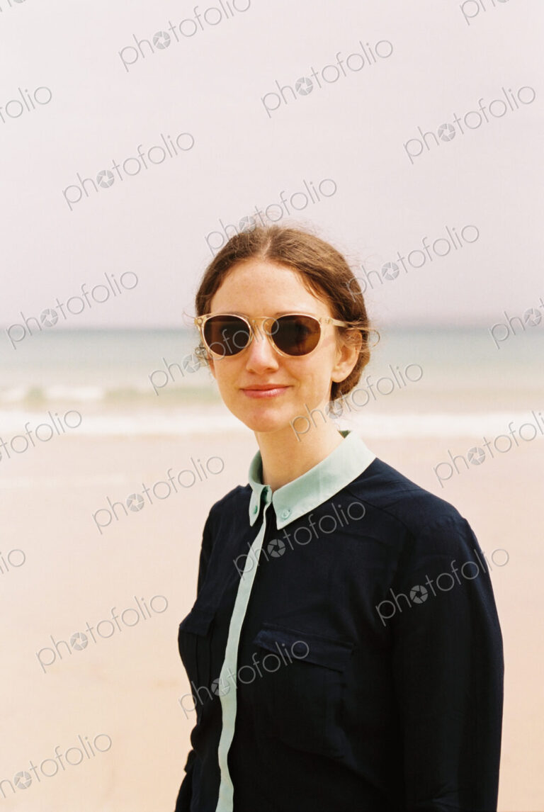 A woman wearing sunglasses on a beach.