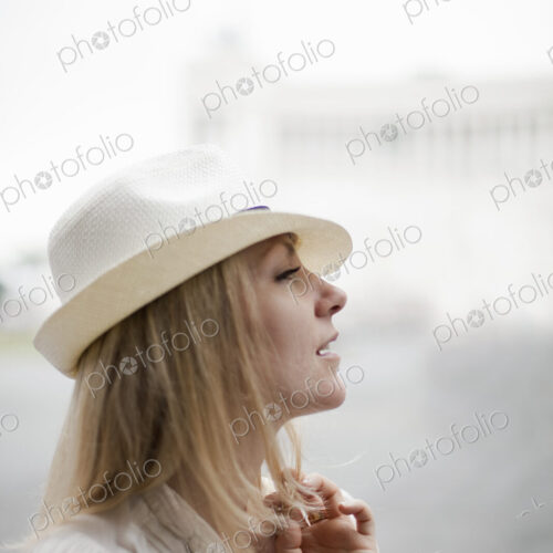 A woman with blonde hair wearing a cream panama hat.