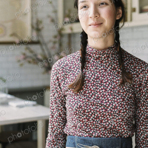 A woman with braids wearing an apron, a waitress in a restaurant. A woman with braids wearing an apron, a waitress in a restaurant.