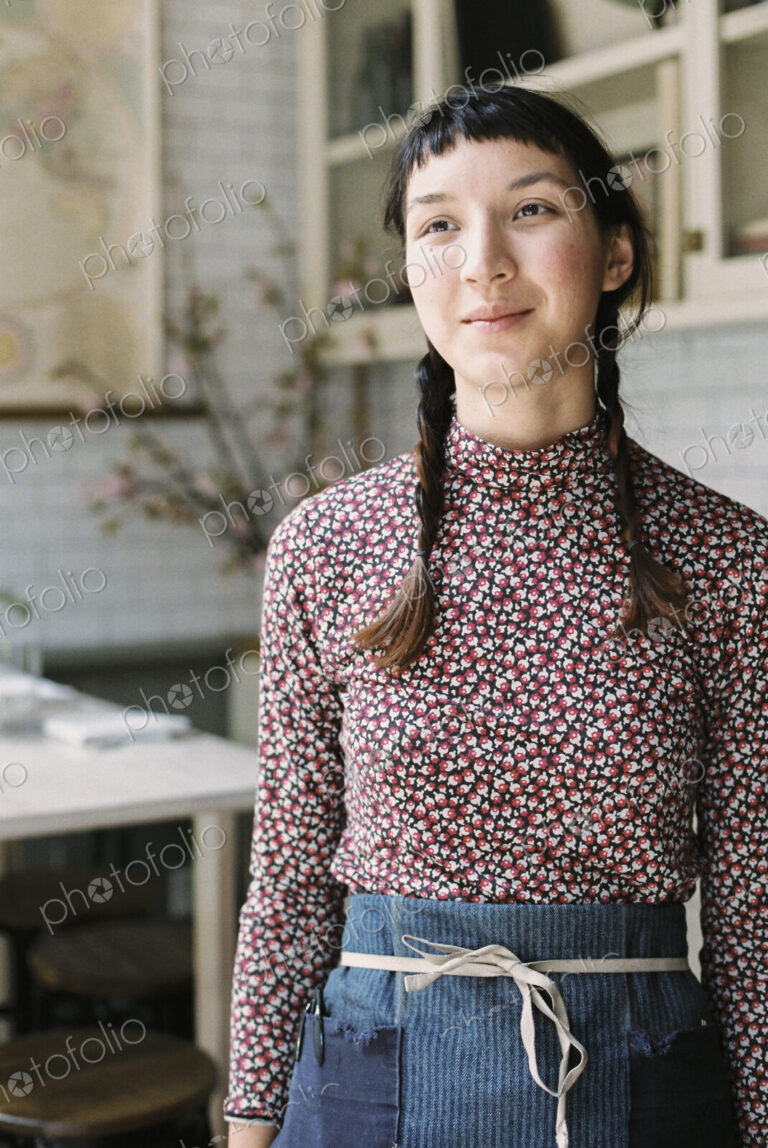 A woman with braids wearing an apron, a waitress in a restaurant.