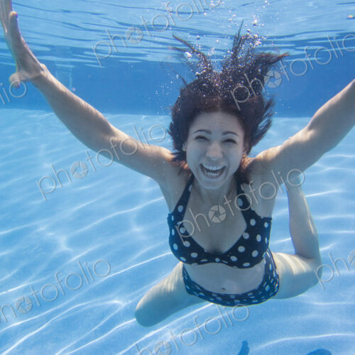 A woman with long black hair wearing a spotted bikini, underwater. A woman with long black hair wearing a spotted bikini, underwater.