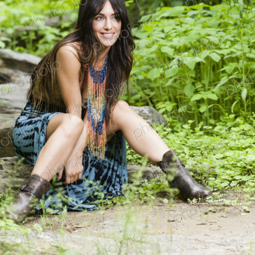A woman with long brown hair outdoors in woodland.