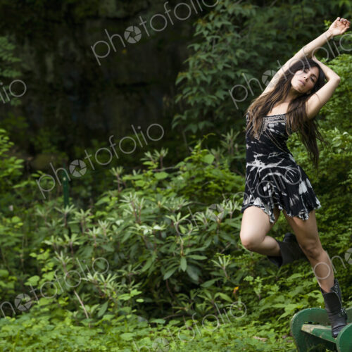 A woman with long brown hair outdoors in woodland.