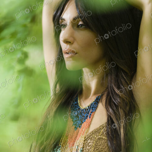 A woman with long brown hair outdoors in woodland with her arms above her head. A woman with long brown hair outdoors in woodland with her arms above her head.