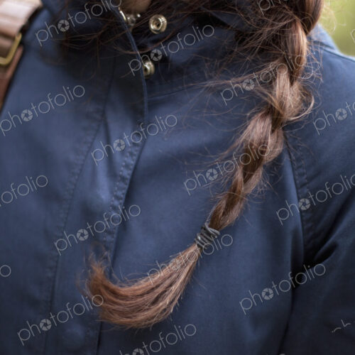 A woman with long brown hair plaited in a braid. Wearing a blue leather jacket. Close up. A woman with long brown hair plaited in a braid. Wearing a blue leather jacket. Close up.