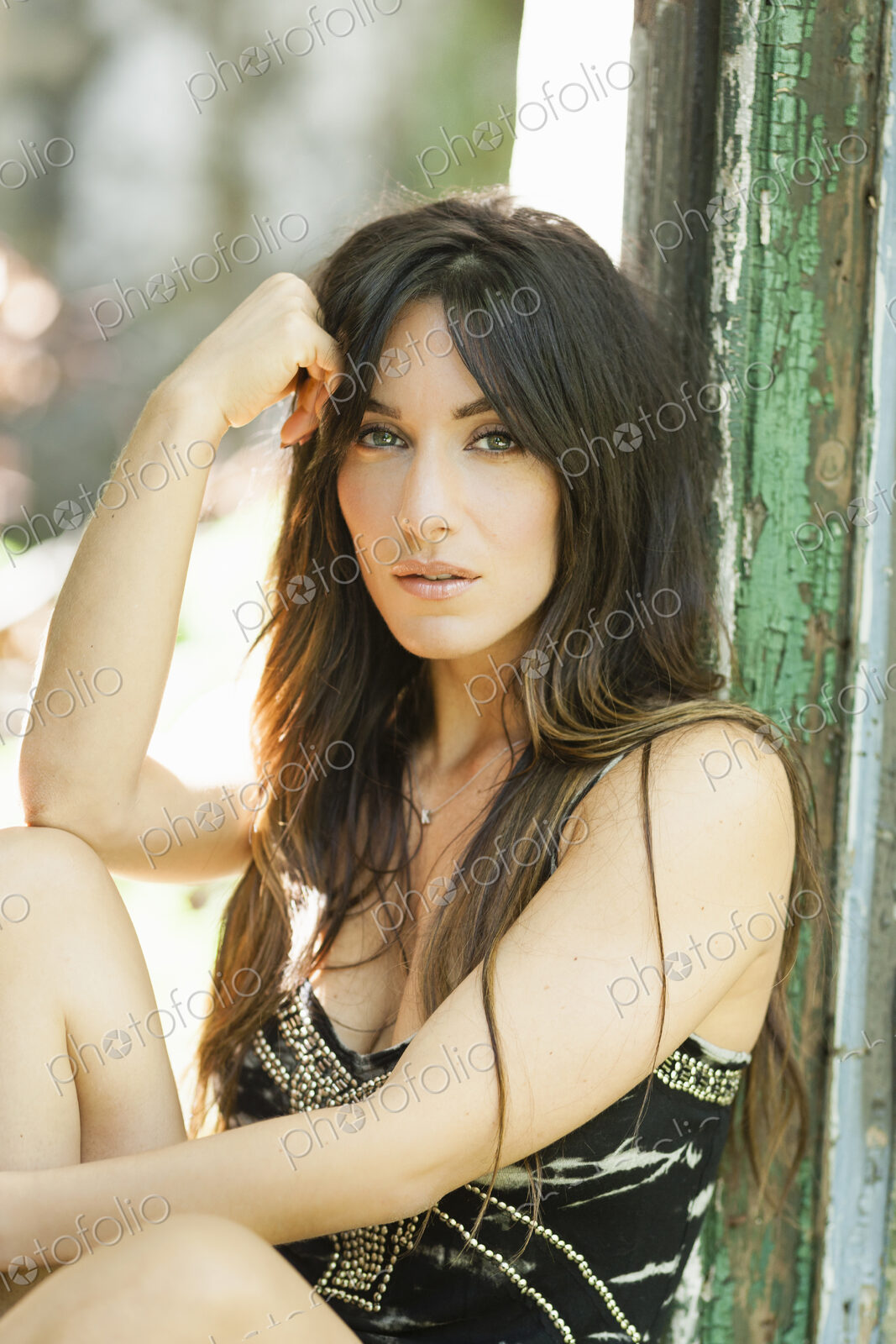 A woman with long brown hair sitting against a door post.