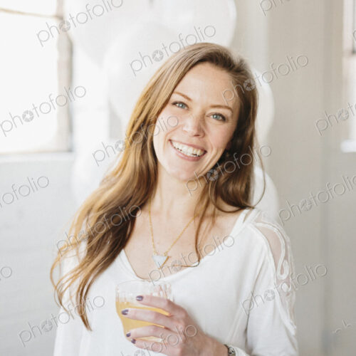A woman with long hair in a white blouse, holding a drink. White balloons, party… A woman with long hair in a white blouse, holding a drink. White balloons, party…