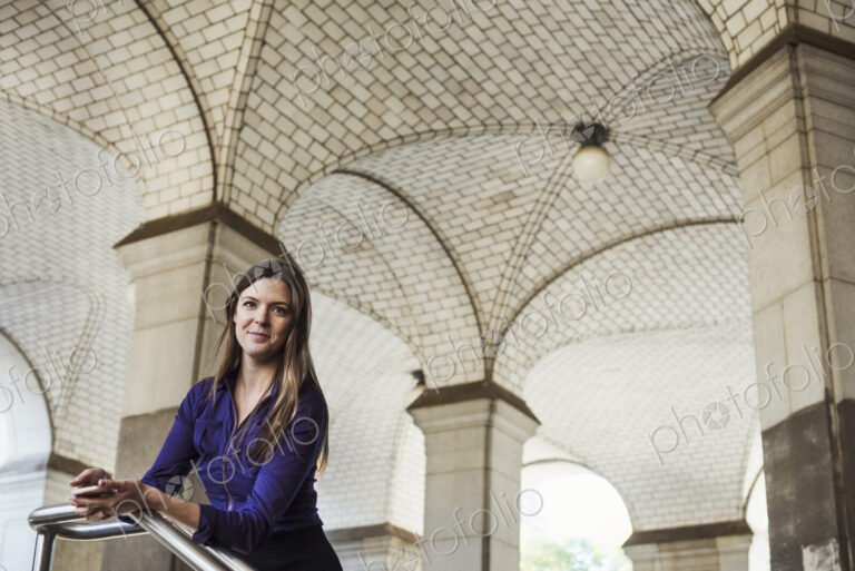 A woman with long hair standing under an arched ceiling.