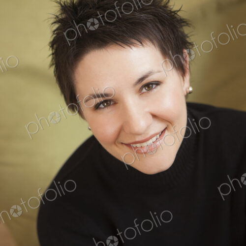 A woman with short spikey brown hair, wearing a black turtleneck sweater. Smiling and… A woman with short spikey brown hair, wearing a black turtleneck sweater. Smiling and…