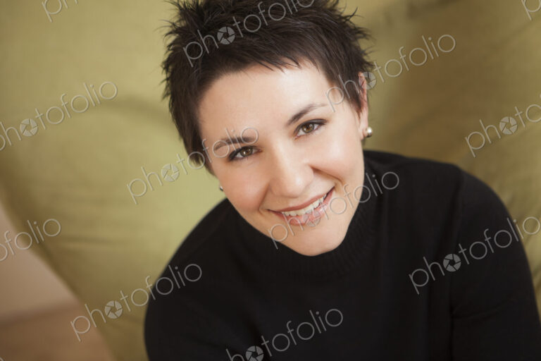 A woman with short spikey brown hair, wearing a black turtleneck sweater. Smiling and…