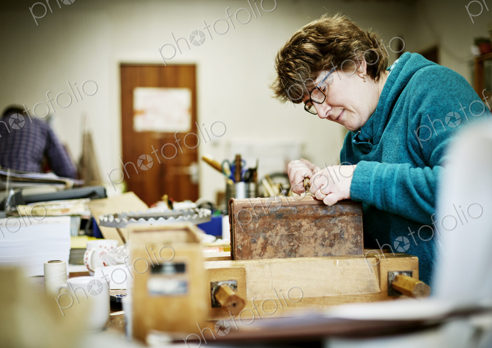 A woman working at a bench on the binding of a book in need of restoration.