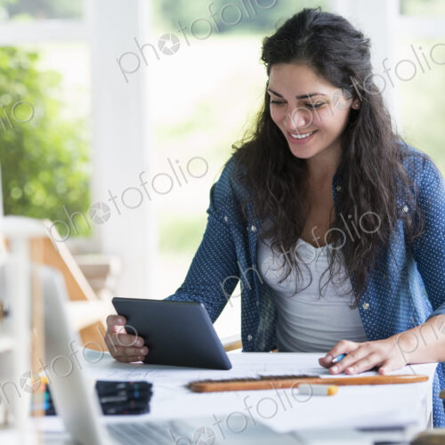 A woman working at a table, using a digital tablet. A woman working at a table, using a digital tablet.