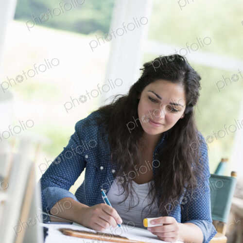 A woman working at a table, using a digital tablet.